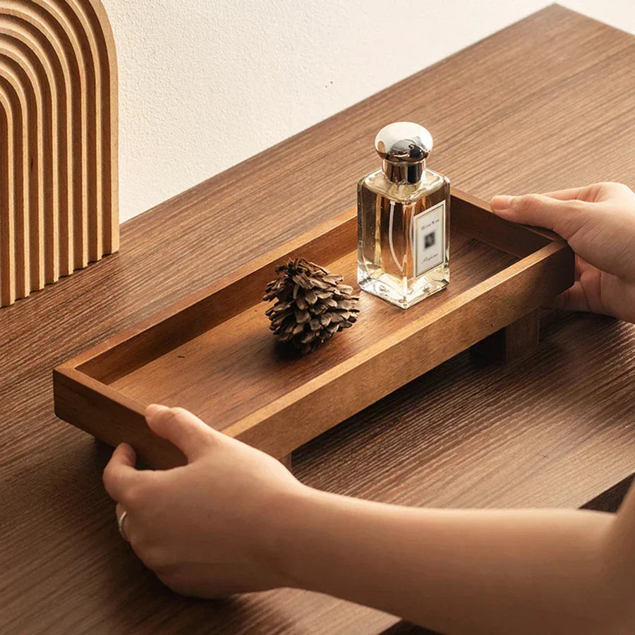 The Grove oak serving tray styled with a pine cone and perfume bottle.