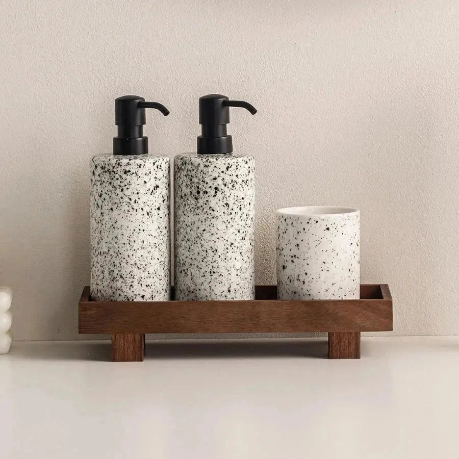 The Grove Oak Wood Serving Tray with speckled white dispensers and a white cup for modern bathroom decor.